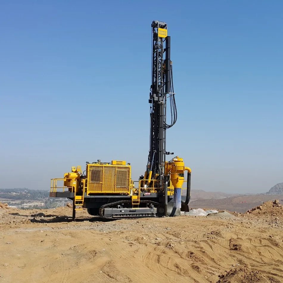 Yellow crawler blast-hole drilling rig with a raised mast on a mine bench