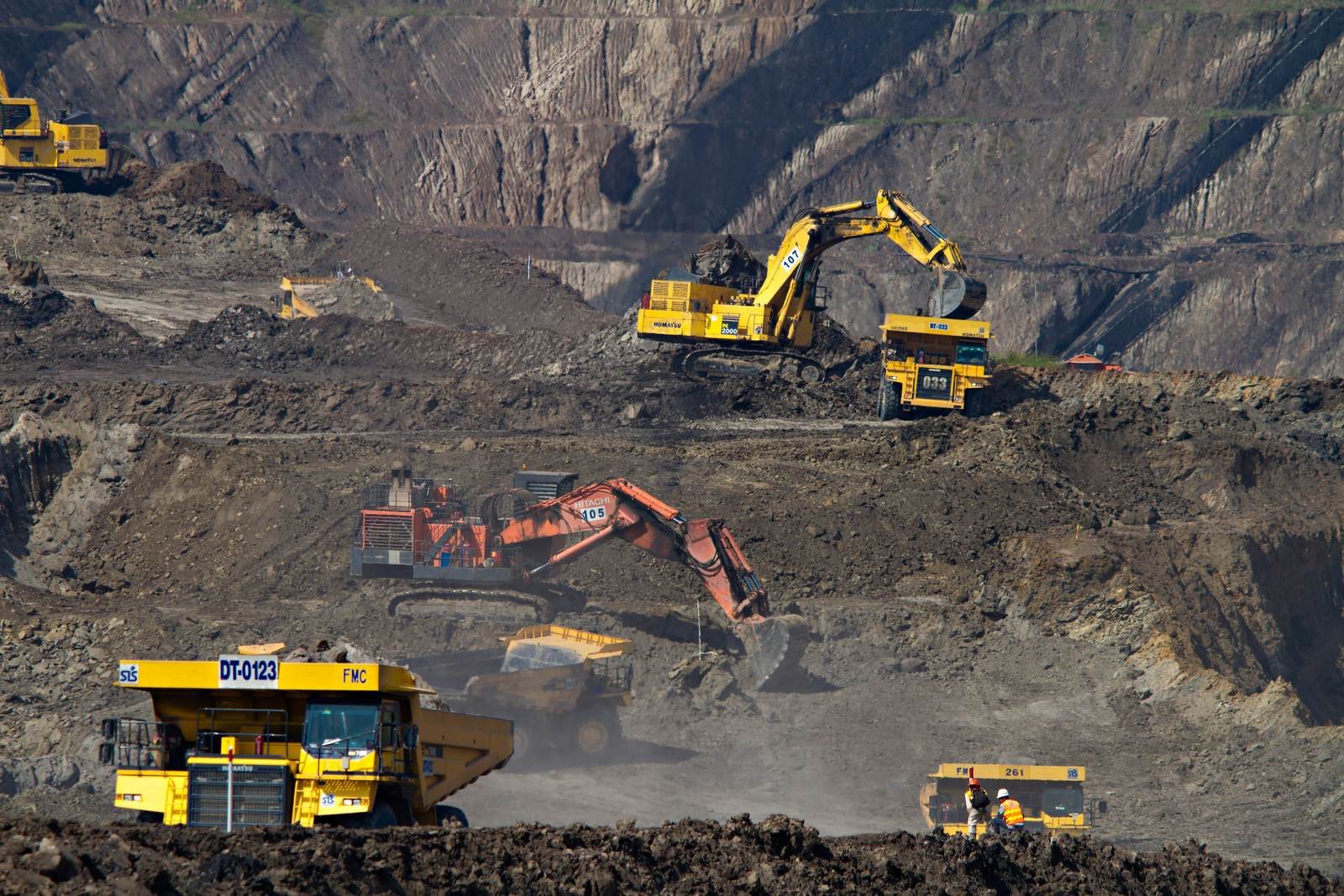 Excavators and haul trucks working in a large open-pit mine
